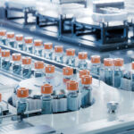 Vaccine Production Facility. Medication Manufacturing Process. Glass Vials with Orange Caps on Conveyor Belt. Medical Ampoule Production Line at Modern Pharmaceutical Factory.