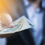 Businessman holding USD banknote for payment.US dollar is main and popular currency of exchange in the world. Investment and saving concept.