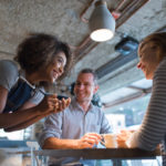 Happy waitress taking an order at a restaurant and talking to customers