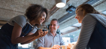 Happy waitress taking an order at a restaurant and talking to customers