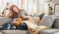 Mother taking care of sleepy child while sitting on couch in the living room